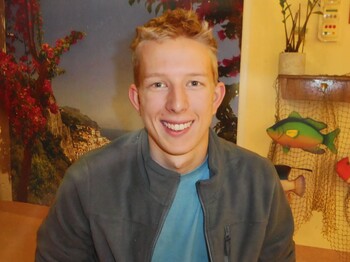 ein junger blonder Mann lächelt freundlich in die Kamera