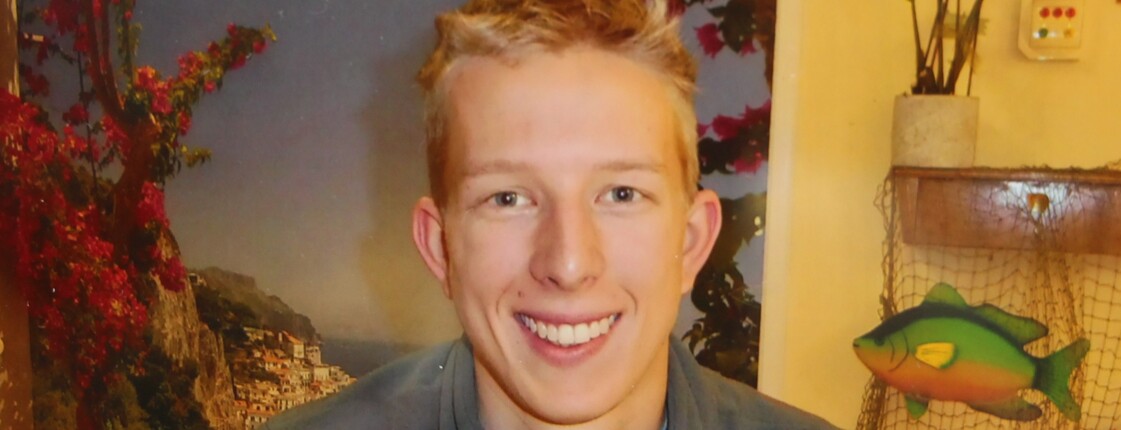 ein junger blonder Mann lächelt freundlich in die Kamera