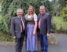 Bürgermeister Josef Niggas, Caritas-Direktorin Nora Tödtling-Musenbichler und Hausleiter Josef Url stehen lächelnd nebeneinander. Im Hintergrund ist eine gepflegte Grünanlage mit üppiger Bepflanzung zu sehen.