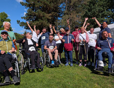 Gruppe von Teilnehmenden, einige im Rollstuhl, posiert beim Charity Run in Friesach auf einer Wiese.