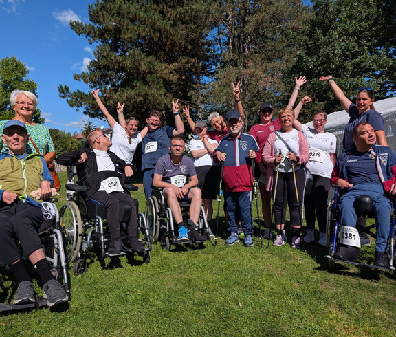 Gruppe von Teilnehmenden, einige im Rollstuhl, posiert beim Charity Run in Friesach auf einer Wiese.