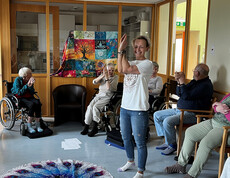 Gemeinsame Dehnübung mit seitlichem Armheben bei einer Seelenyoga-Stunde mit Senior*innen.