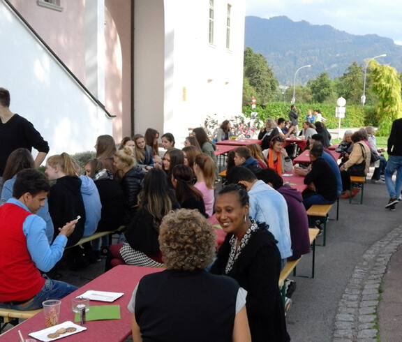Zahlreiche Leute sitzen im Freien auf Bänken beim langen Tag der Flucht.