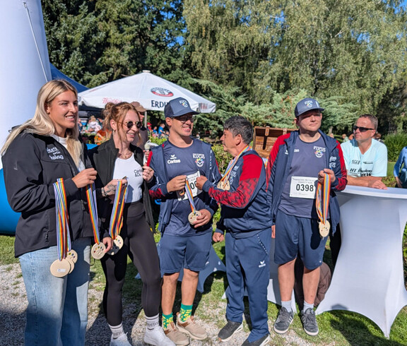 Hannah Ladinig und Mitglieder der KUGIS präsentieren Finisher-Medaillen beim Charity Run in Friesach.
