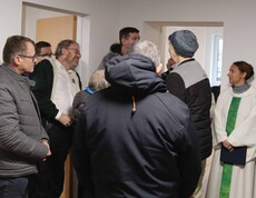 Viele Personen und die Seelsorgerin in einem neuen Haus.