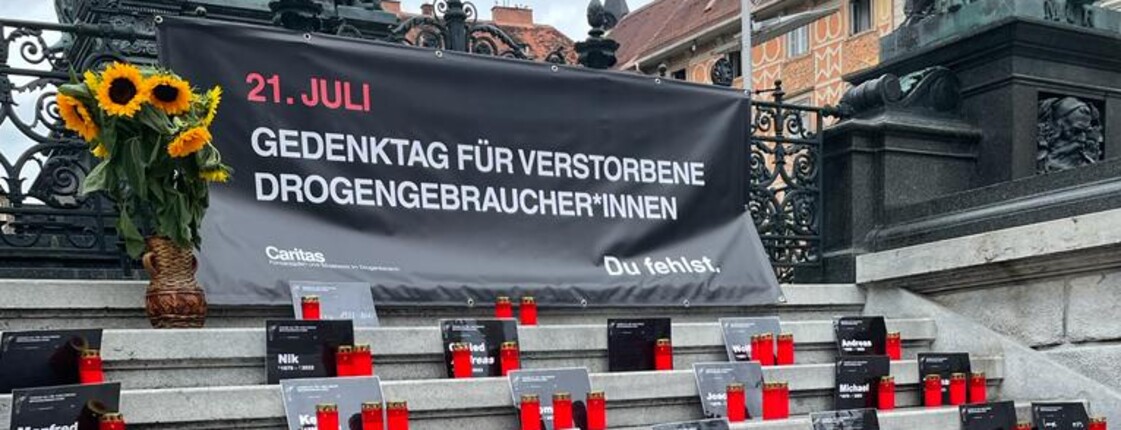 Kerzen und ein Plakat erinnern am Grazer Hauptplatz an verstorbene Drogengebraucher*innen
