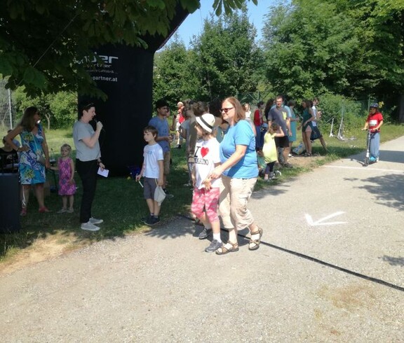 Kinder und Begleitpersonen bewegen sich entlang der Laufstrecke einer Sportveranstaltung und nehmen gemeinsam am Event teil.