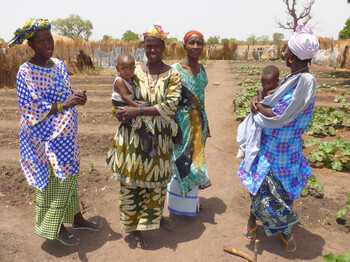 Frauen mit ihren Kindern stehen in einem landwirtschaftlichen Projekt in der Region Tambacounda, Senegal.