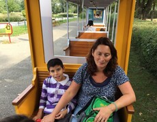 Eine erwachsene Begleitperson und ein Kind sitzen in einem Wagen der Parkeisenbahn und fahren gemeinsam durch den Donaupark.