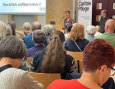 Caroline Leitner spricht auf einer Bühne, Menschen sitzen davor in Reihen.