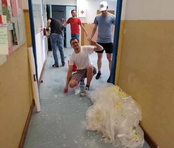 Mehrere Personen unterstützen eine Renovierungsaktion im Gebäude und helfen gemeinsam bei Aufräum- und Umbauarbeiten.
