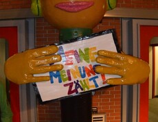 Eine große Figur hält eine Botschaft mit der Aufschrift Meine meine Meinung zählt. Die Figur stellt einen Jungen dar und trägt grüne Kopfhörer.