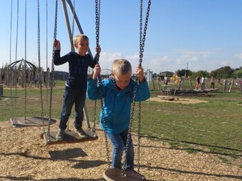 Kinder balancieren auf hängenden Trittplatten einer Motorikstation im Freien und trainieren spielerisch Gleichgewicht und Koordination.