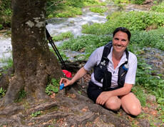 Frau legt bemalten Stein bei einem Baum neben einem Fluss ab.