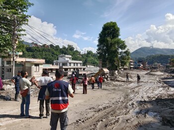 Caritas-Mitarbeitende begutachten eine von Schlamm und Geröll verwüstete Straße nach der Flut in Nepal.