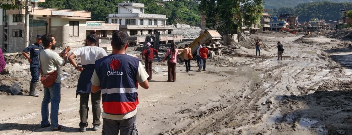Caritas-Mitarbeitende begutachten eine von Schlamm und Geröll verwüstete Straße nach der Flut in Nepal.
