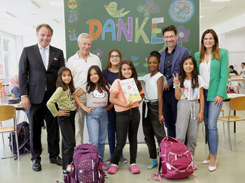 Kinder und Erwachsene vor einer Tafel mit „DANKE“ bei Spendenübergabe im Caritas-Lerncafe.