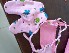 Zwei fertig genähte, rosafarbene Stoffbinden mit buntem Hasenmuster liegen auf einer Holzoberfläche; die Bindebänder sind deutlich sichtbar.