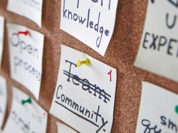 Post-it-Zettel hängen mit punkten Stecknadeln auf einer Pinwand.