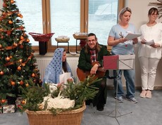 Mitarbeitende und Zivildienstleistende gestalten Krippenspiel neben geschmücktem Weihnachtsbaum