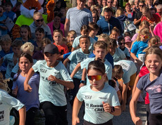 Viele Kinder starten gemeinsam zu einem Lauf, Zuschauer*innen säumen die Strecke.