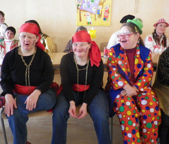 Fasching in er Werkstätte Bludenz. Menschen mit Behinderung sind verkleidet und geschminkt. Sie schneiden dabei fröhliche Grimassen. 