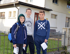 Drei junge Buben stehen im Freien für ein Gruppenfoto.