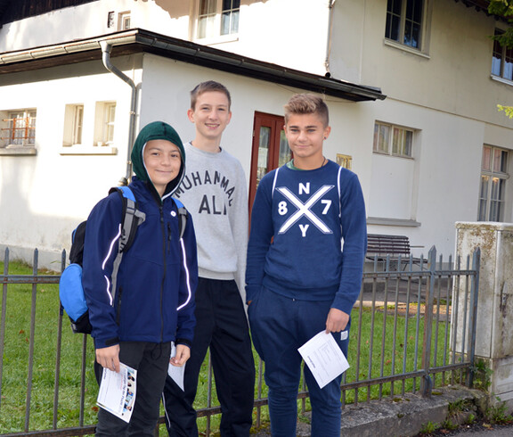 Drei junge Buben stehen im Freien für ein Gruppenfoto.