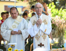 Geistliche halten eine Messe im Garten des Pflegewohnhauses, Gäste und Kinder stehen im Hintergrund.