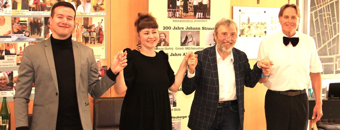 Vier Mitglieder des Künstlerkollegiums Manfred Grössler stehen nebeneinander vor den Bewohnerinnen und Bewohnern des Caritas Pflegewohnhauses Graz-Straßgang. Sie halten sich an den Händen, lächeln und verbeugen sich gemeinsam als Zeichen des Dankes für den herzlichen Applaus des Publikums.