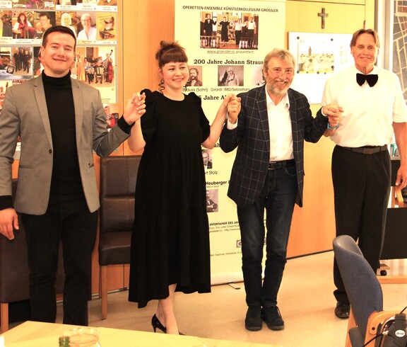 Vier Mitglieder des Künstlerkollegiums Manfred Grössler stehen nebeneinander vor den Bewohnerinnen und Bewohnern des Caritas Pflegewohnhauses Graz-Straßgang. Sie halten sich an den Händen, lächeln und verbeugen sich gemeinsam als Zeichen des Dankes für den herzlichen Applaus des Publikums.