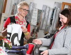 Zwei junge Frauen befinden sich in einem der Carla Shops. Die Verkäuferin verpackt und verrechnet die Auswahl der Kundin.