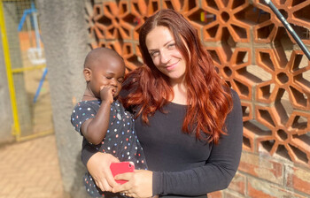 Eine junge Frau hält ein Kleinkind im Hof des Nsambya Babies Home in Kampala 