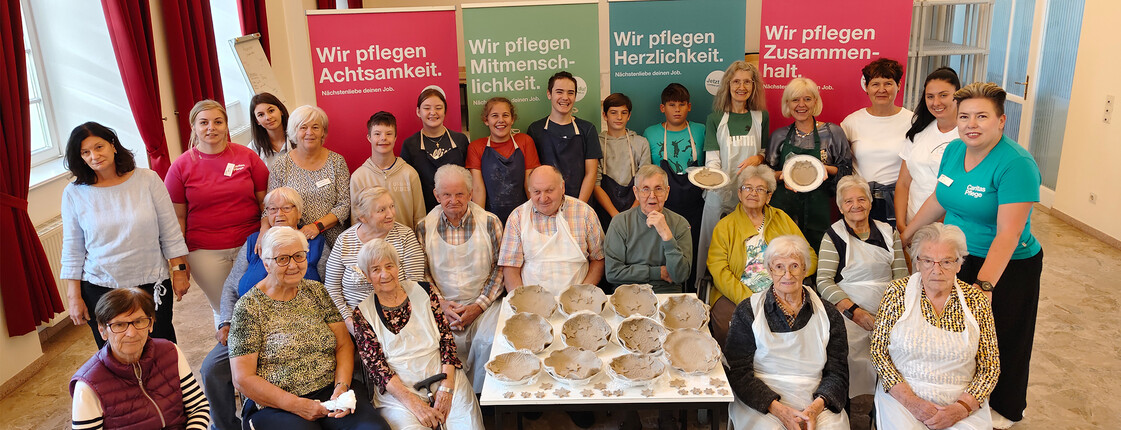 Gruppenfoto im Haus Elisabeth in St. Andrä mit Besucher*innen und Bewohner*innen beim kreativen Arbeiten mit Ton.