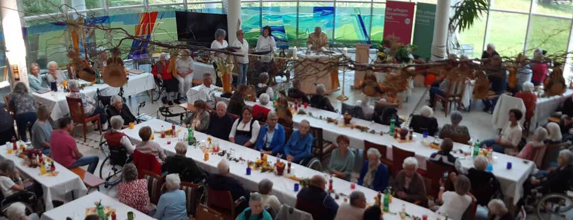 Zahlreiche Senior*innen und Gäste sitzen an langen Tafeln beim Herbstfest im Haus Suavitas.