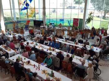 Zahlreiche Senior*innen und Gäste sitzen an langen Tafeln beim Herbstfest im Haus Suavitas.