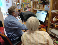 Zwei Personen sitzen vor einem Computerbildschirm in der Bücherei und lernen gemeinsam.