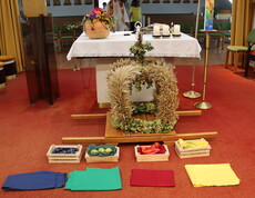 In einer Kapelle im Innenraum auf rotem Tepich liegen ein paar Gaben sowie die Erntekrone