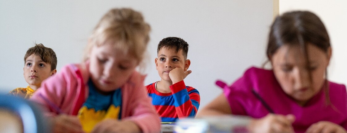 Mehrere Kinder sitzen in einem Klassenraum und konzentrieren sich auf ihre Aufgaben.