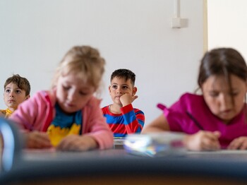 Mehrere Kinder sitzen in einem Klassenraum und konzentrieren sich auf ihre Aufgaben.