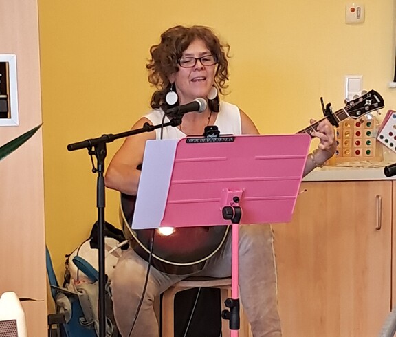 Eine Musikerin begleitet die Veranstaltung zum Tag der Demenz mit Gesang und Gitarrenspiel und lädt die Bewohner*innen zum gemeinsamen Mitsingen ein.