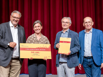 Vier Personen stehen auf einer Bühne und erhalten einen Preis.