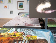 Verschiedene Bilder liegen auf einem Tisch im Hintergrund ist ein schwarzer Monitor mit einem hellen Kreis