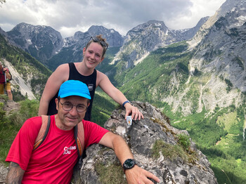 Mann und Frau legen einen bemalten Stein auf einem Berggipfel ab. 