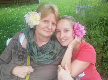 Bewohnerin mit Mitarbeiterin des Hauses St. Elisabeth mit herbstlichen Blumen im Haar