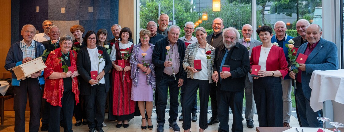 In einem Veranstaltungsraum mit großer Glasfassade stehen viele Personen zu einem Gruppenfoto zusammen.