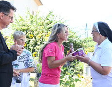 Geschenkübergabe an eine Ordensschwester bei einer Ansprache im Garten des Pflegewohnhauses.