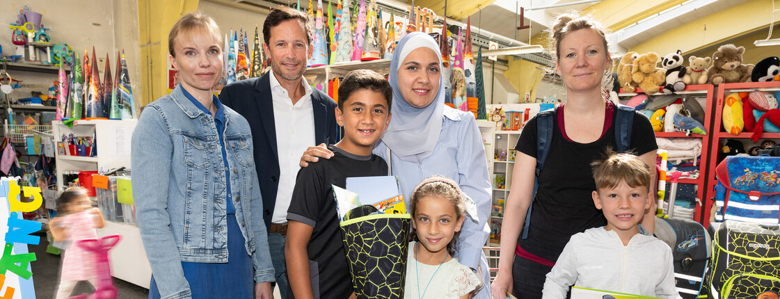 Caritasdirektor Klaus Schwertner und Leiterin der Bildungsprojekte Martina Polleres-Hyll mit Familien, die im carla günstige Schulsachen einkaufen