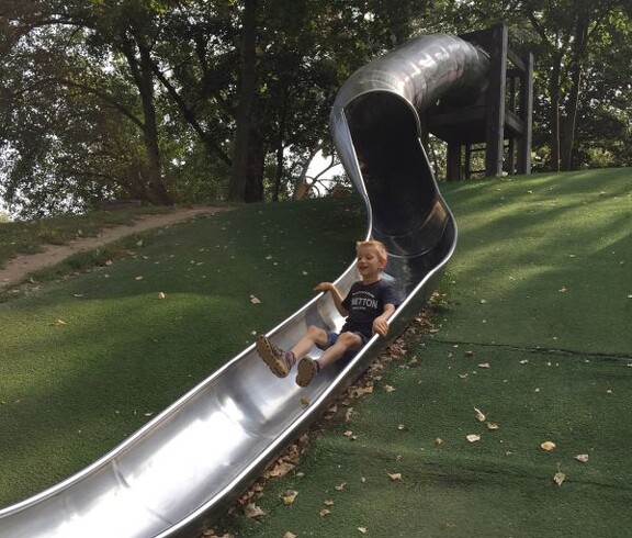 Ein Kind rutscht eine lange Tunnelrutsche hinunter und spielt auf einer großzügigen Spielanlage im Donaupark.