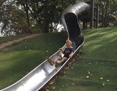 Ein Kind rutscht eine lange Tunnelrutsche hinunter und spielt auf einer großzügigen Spielanlage im Donaupark.